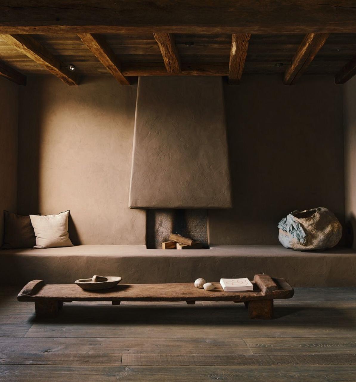 Interior con chimenea de adobe y vigas de madera recuperada